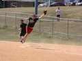 Softball Against Humanity first baseman leaps to prevent an overthrow against the Bones Brigade.